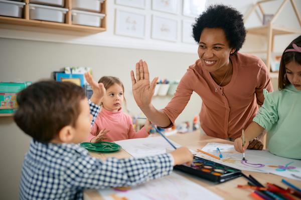 A teacher high-fives a young student in a...