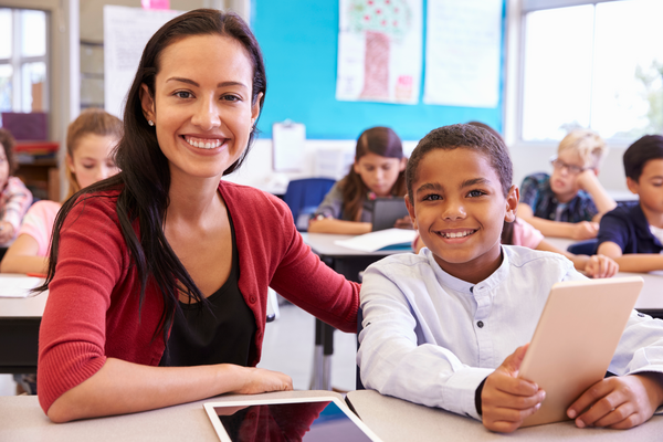 A teacher and student sit side-by-side in a...