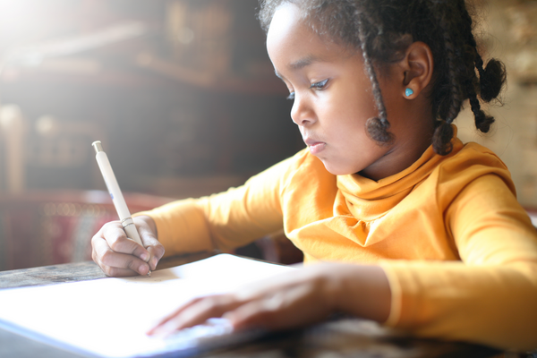 A young girl, deep in concentration, works with a...